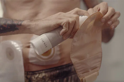 man applying a spray to an ostomy pouch
