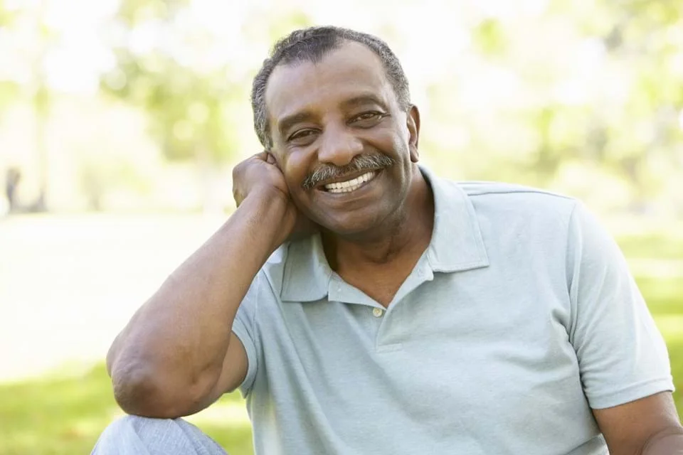 um homem sorrindo com a mão na cabeça